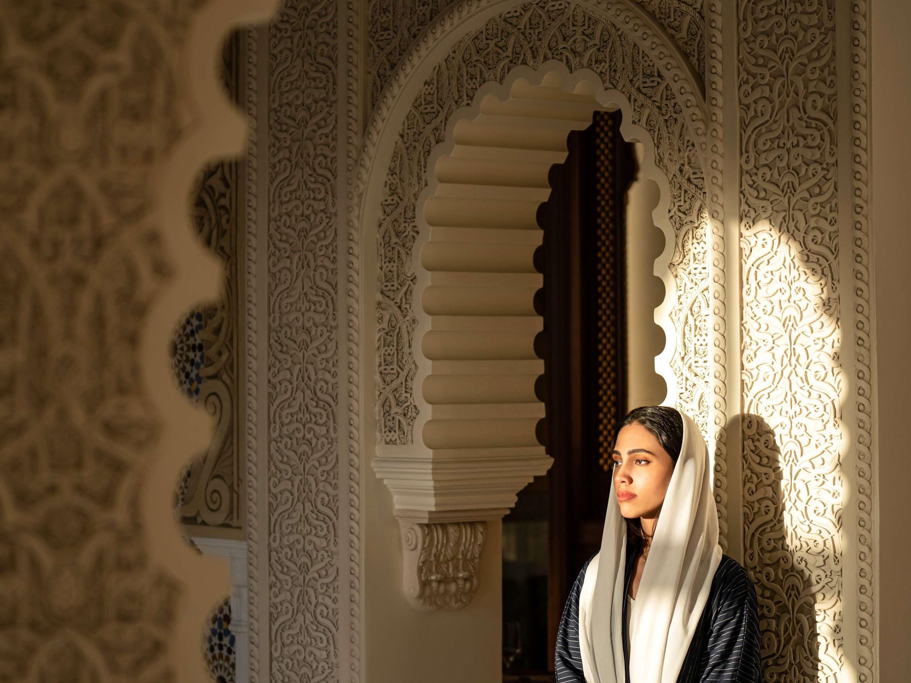 A person standing in an ornate doorway with intricate patterns and a column.