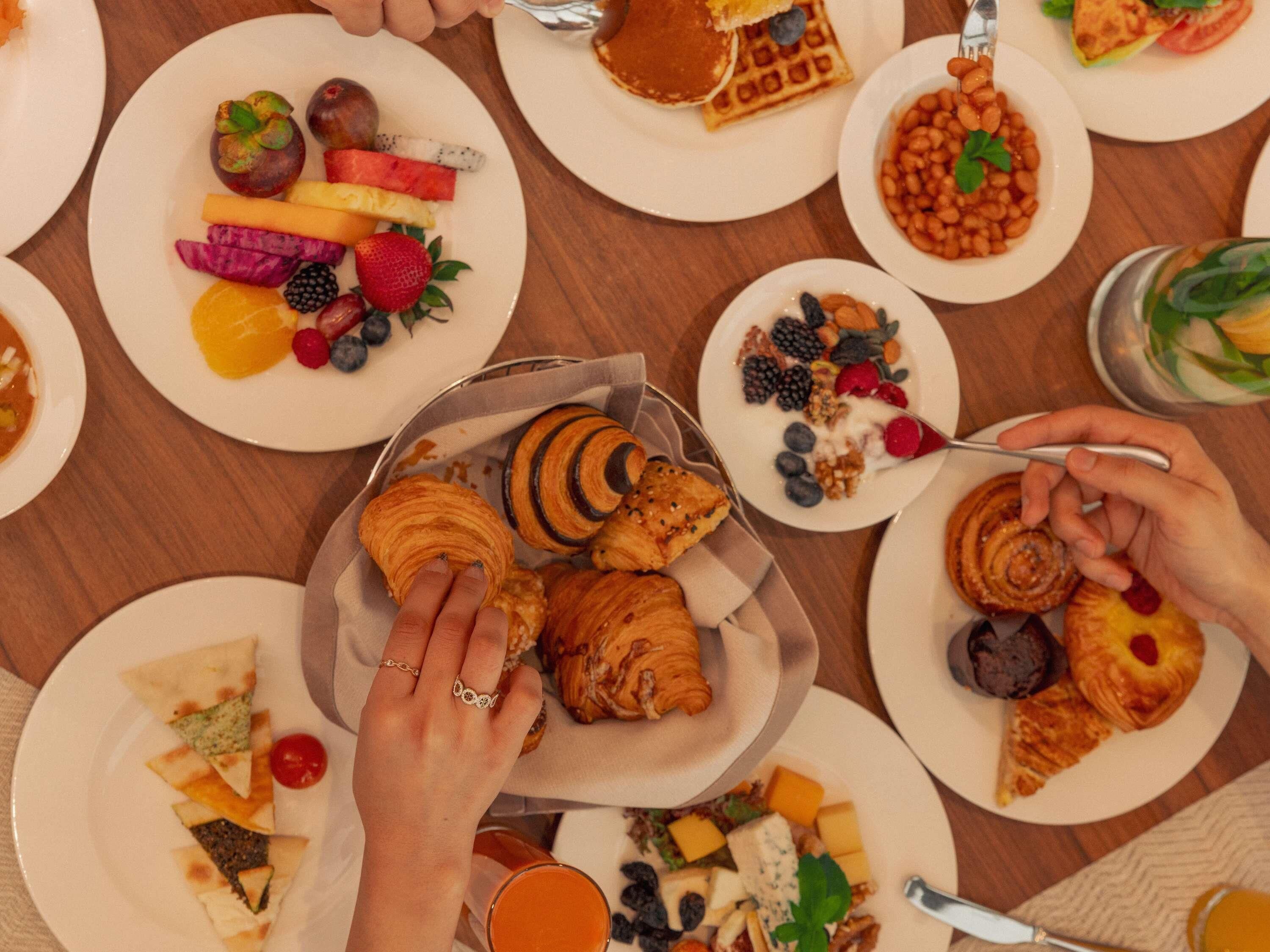 A breakfast buffet with various food items and a person serving themselves.