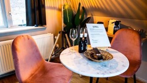 A cozy room with a round table, two chairs, a lamp, a plant, and a menu on the table. - Bambu Sleep Boutique double room 4 (Haarlem)