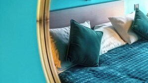 A bedroom with a mirrored ceiling, a bed with pillows, and a teal wall. - Bambu Sleep Boutique double room 3 (Haarlem)