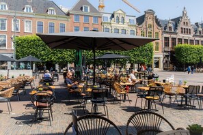Un café al aire libre con mesas y sillas, rodeado de edificios históricos.