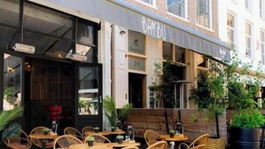 Un restaurante con terraza, fachada de ladrillo y un letrero que dice 'BAMBU'.