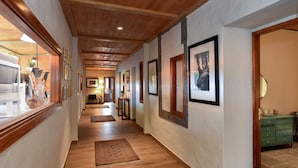 A hallway with wooden floors, framed pictures on the walls, and a green dresser in the background.
