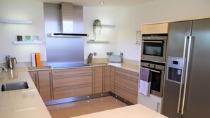 A modern kitchen with a stainless steel refrigerator, double ovens, and a microwave. - Annapurna -  a house that sleeps 8 guests  in 4 bedrooms (Portpatrick, Stranraer)