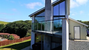 A modern two-story house with large glass windows, a prominent chimney, and a view of a green landscape. - Annapurna -  a house that sleeps 8 guests  in 4 bedrooms (Portpatrick, Stranraer)