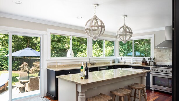A kitchen with a large island, bar stools, a built-in oven, and a view of the outdoors. - Enjoy Newport, stunning beaches, hot-tub, & relax at the lovely Coastal Hideaway (Middletown)