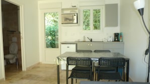 Cocina compacta con microondas, lavamanos y ventana con vistas a zonas verdes.