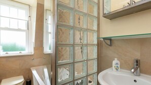 A bathroom with a toilet, a glass shower enclosure, and a sink with a mirror above it. - Rosebery Place in the Heart of Gullane (Gullane)