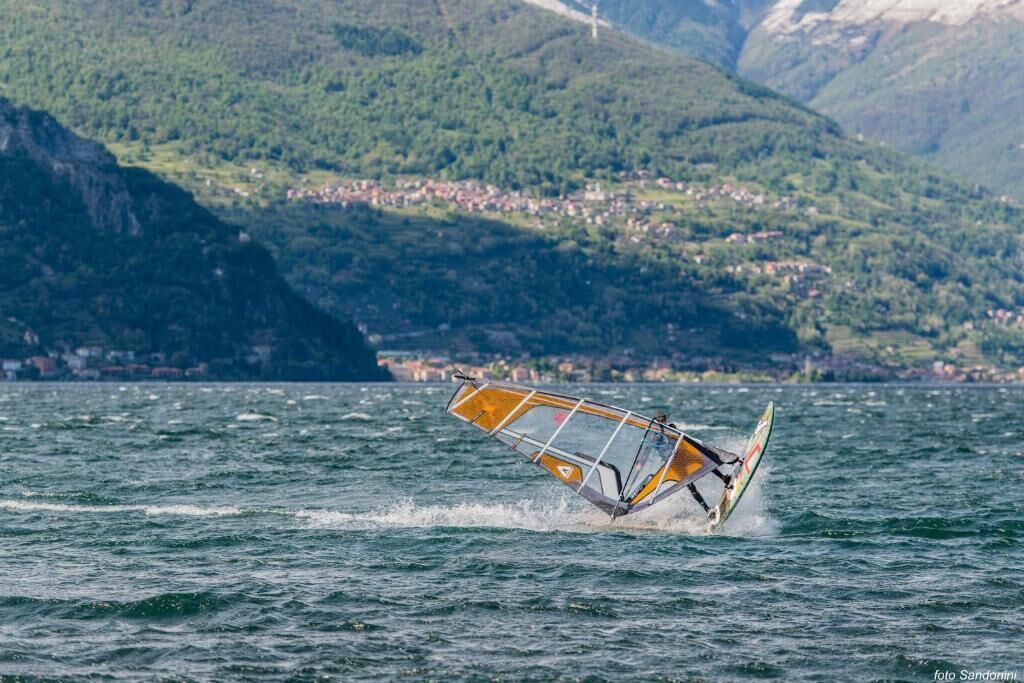 Windsurfen auf einem See vor einer Bergkulisse.