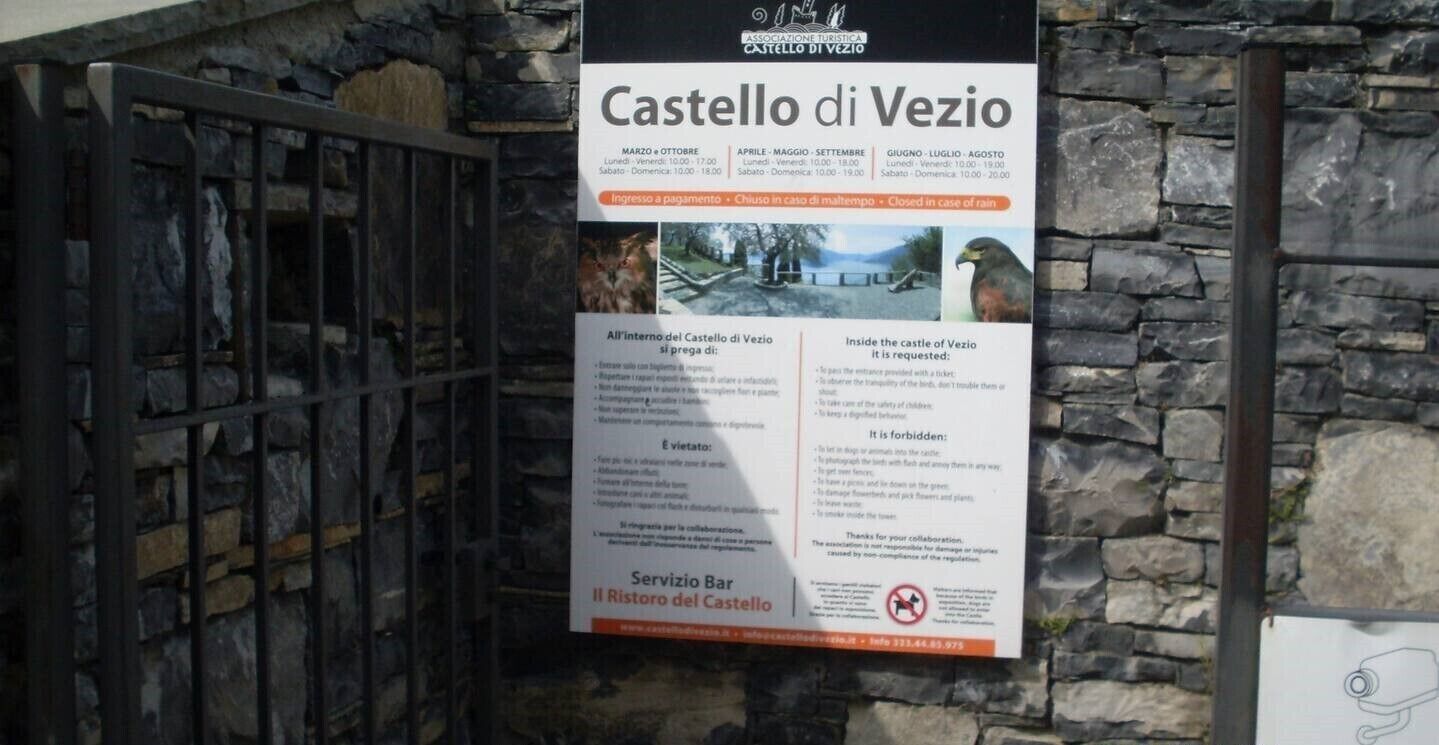Een bordje voor het Castello di Vezio met openingstijden en een regels voor bezoekers.