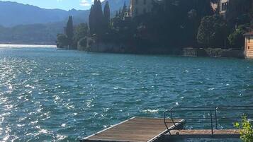 A wooden dock extending into a calm lake with a backdrop of mountains and buildings.