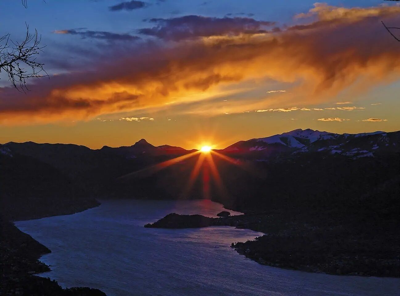 Ein Sonnenuntergang über einer gebirgigen Landschaft mit einem Fluss.