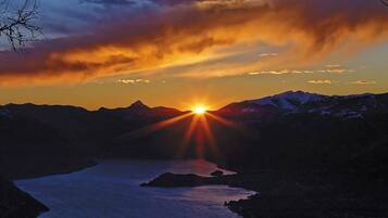 Ein Sonnenuntergang über einer gebirgigen Landschaft mit einem Fluss.