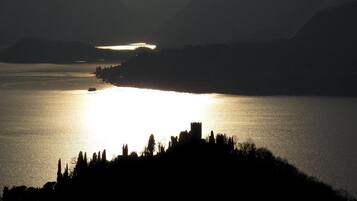 A silhouette of a castle on a hill overlooking a calm lake at sunset.