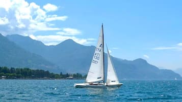 Een zeilboot met registratienummer 'ATI 130' op een wateroppervlak, met bergen op de achtergrond.