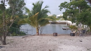 A sandy beach area with a palm tree, a fence, and some outdoor furniture. - Island hide away 1 (Freeport)