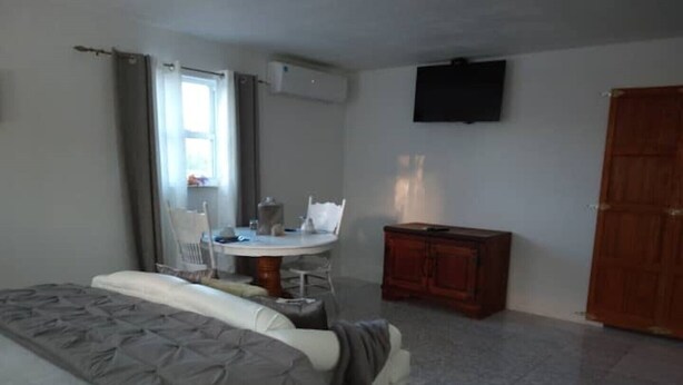 A bedroom with a bed, a dining table, chairs, a TV, and a wardrobe. - Island hide away 1 (Freeport)