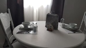 A round dining table with white chairs, a salt and pepper shaker, a small decorative item, and a candle holder. - Island hide away 1 (Freeport)