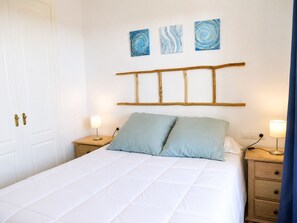 A bedroom with a bed, two bedside tables with lamps, a wooden headboard, and three abstract wall art pieces. - Alboran Hills  5006 Sea & Sun (Manilva)