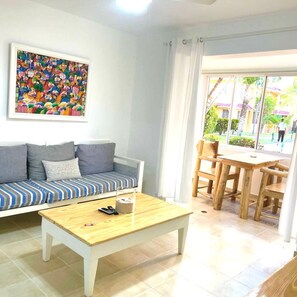 A living room with a sofa, a coffee table, and a dining area with chairs.