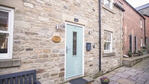A stone building with a light blue door, numbered 4, and a small garden area with potted plants.