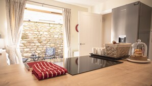 A modern kitchen with a stone wall, a refrigerator, a coffee machine, and a dining area with a table and chairs.