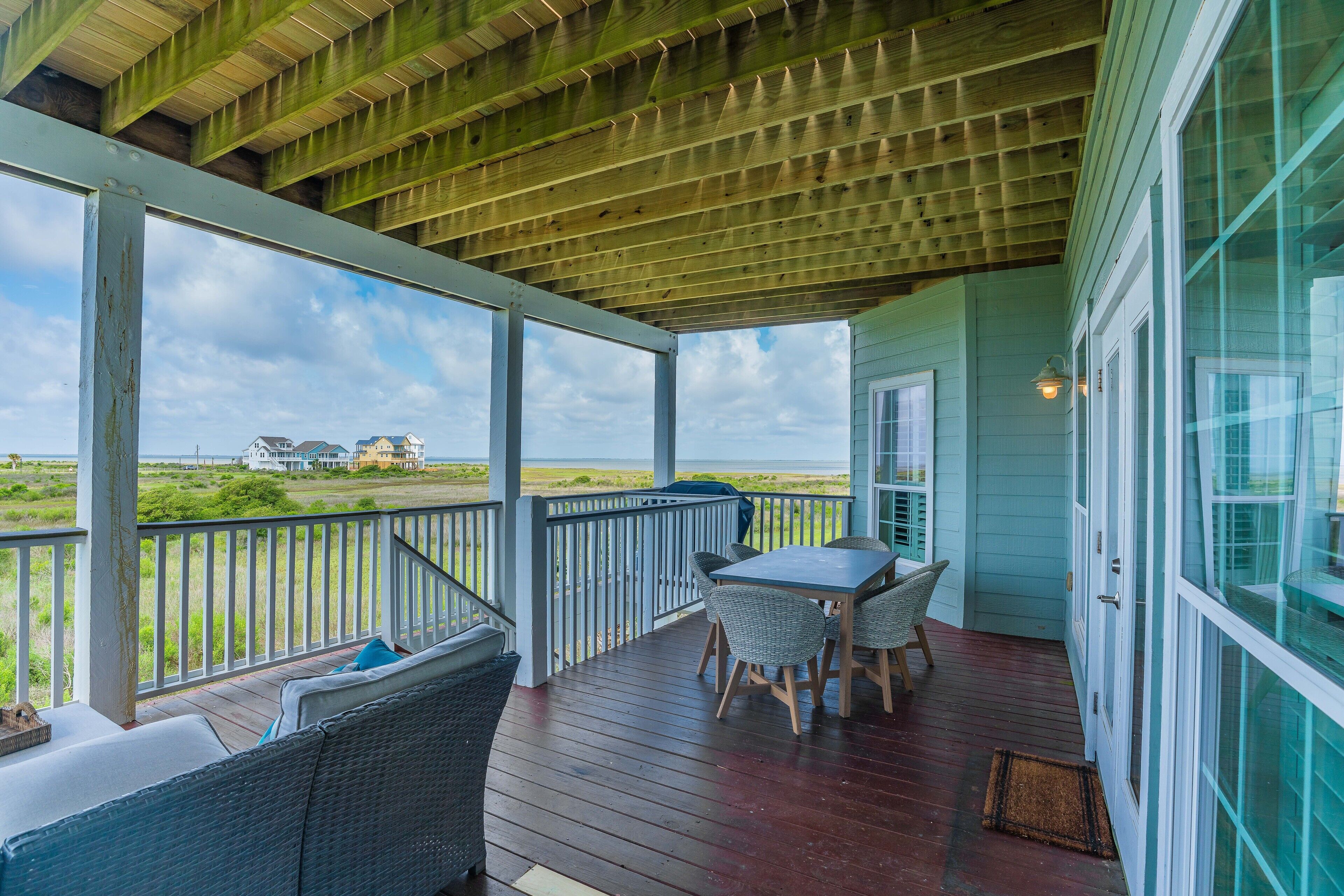 First floor balcony features outdoor dining, sitting area, and gas grill