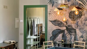 A room with a green-framed door, a table with a book, a hanging light fixture, and a patterned wall. - Cocci Grifoni - Panoramic Wine Resort (Offida)