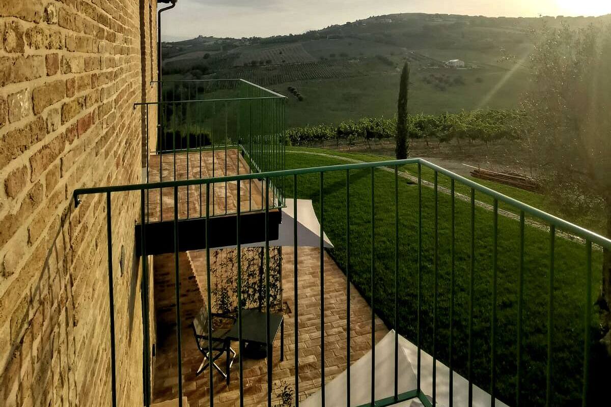 A balcony with a view of a vineyard and hills.