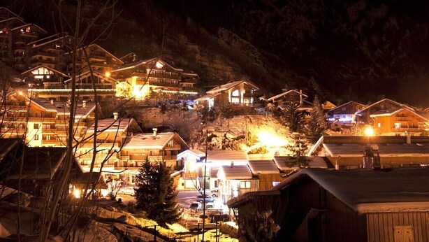 A mountain village at night with illuminated buildings, a ski lift, and a snowy landscape. - AT THE FOOT OF THE CHAMPAGNY EN VANOISE SLOPES LA PLAGNE-PARADISKI PARC DE LA VANOISE (Champagny-en-Vanoise)