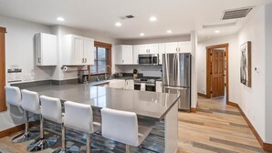 A modern kitchen with white cabinets, stainless steel appliances, and a central island with bar stools.