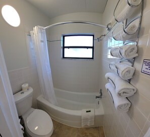 A bathroom with a bathtub, toilet, and a window. - Satellite Motel - Happy Daze 107 (Treasure Island)