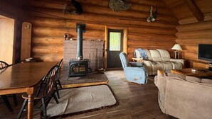Un acogedor interior de cabaña de madera con chimenea, sofá de cuero y mesa de comedor de madera.