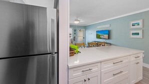 Une cuisine moderne avec des meubles blancs, un réfrigérateur en acier inoxydable et un plan de travail blanc.