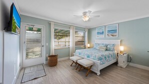 Une chambre à coucher avec un lit, un ventilateur de plafond, une télévision et des œuvres d’art accrochées au mur.