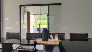 Een moderne keuken met een zwart aanrecht, twee rieten stoelen, een grote spiegel en uitzicht op het landschap.