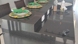 Een lange eettafel met stoelen, groene servetten en borden. Er staan twee flessen op tafel.