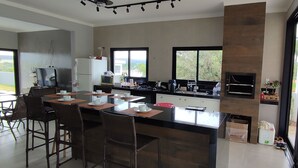 Een moderne keuken met een centraal kookeiland, barkrukken en grote ramen met uitzicht op de omgeving.