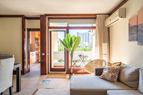 A modern living room with a sofa, a dining table, and a potted plant.