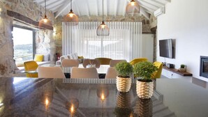 A modern kitchen with a large island, pendant lights, and a stone wall. - Casa do Sobreiro / Casas de Basto (Infesta)