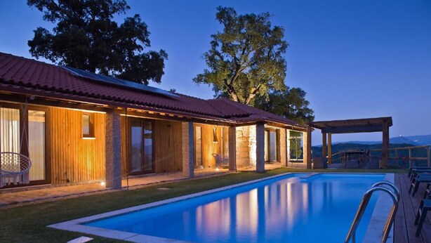 A swimming pool with a wooden deck, a covered patio area, and a building with a red roof. - Casa do Sobreiro / Casas de Basto (Infesta)