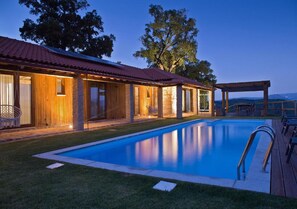 Zwembad met houten terras, overdekte patio en gebouw met rood dak.