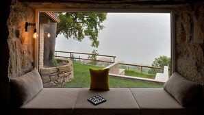A cozy seating area with a stone wall and a view of a grassy landscape. - Casa do Sobreiro / Casas de Basto (Infesta)