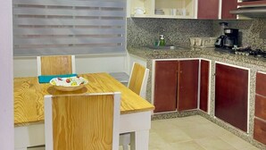 Une cuisine de taille réduite comprenant une table à manger, des chaises et un four à micro-ondes.
