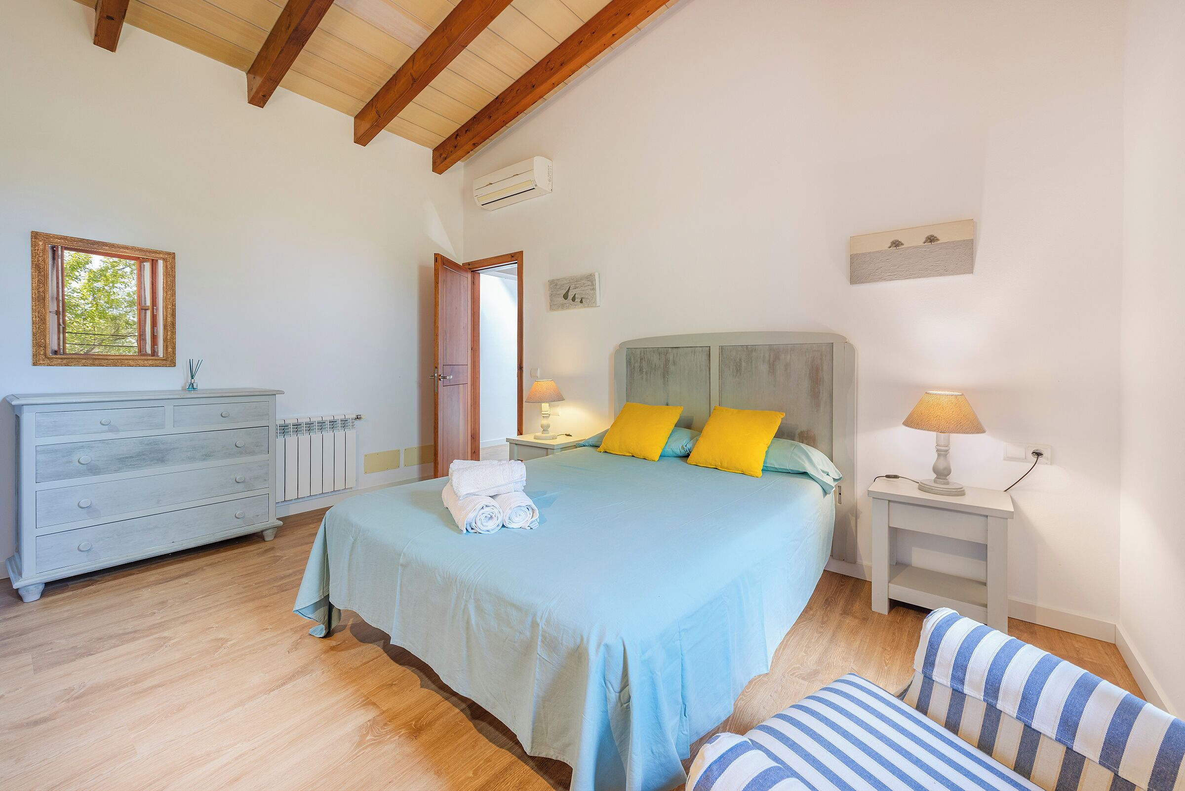 Une chambre à coucher avec un lit, des tables de chevet, une commode et une fenêtre.