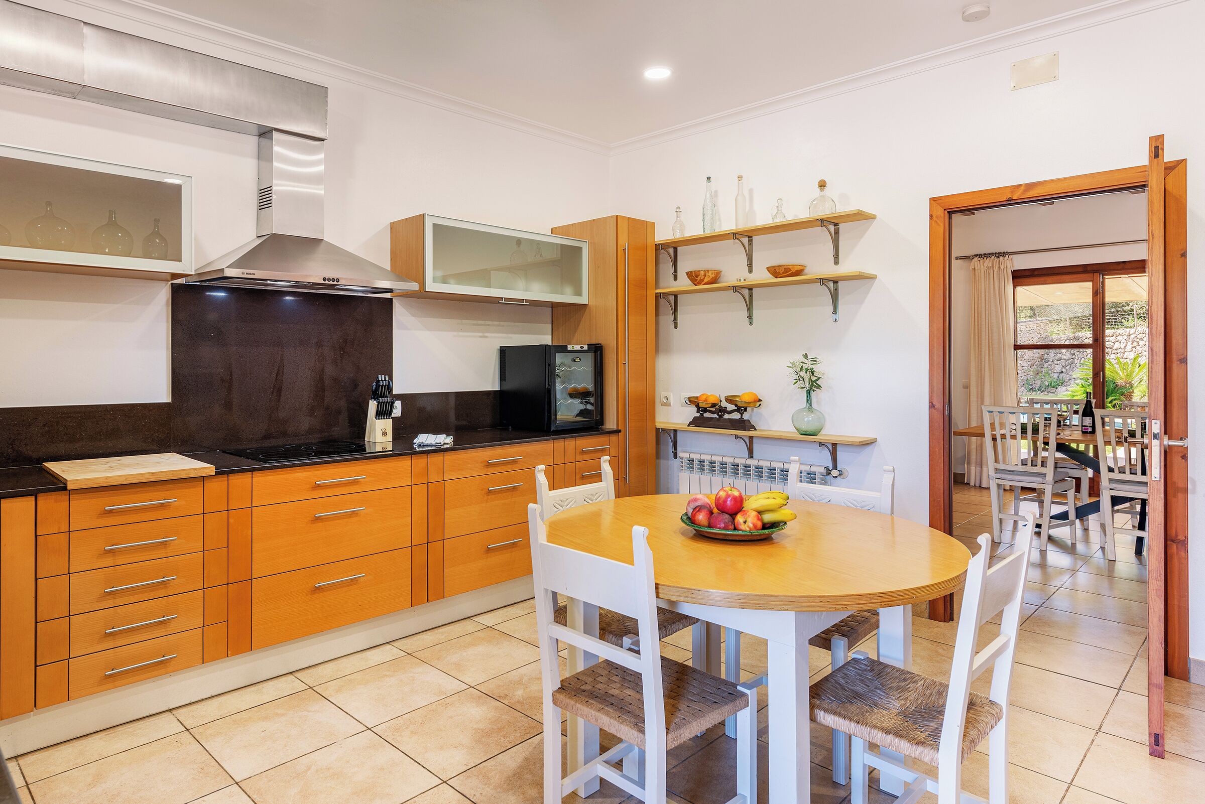 A modern kitchen with wooden cabinets, a black stove, and a dining table with chairs.