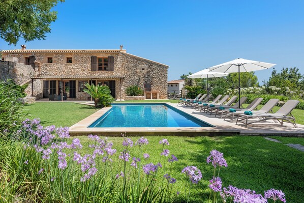 A stone house with a swimming pool, outdoor seating, and lush greenery. - Villa Pontarro (Pollença)