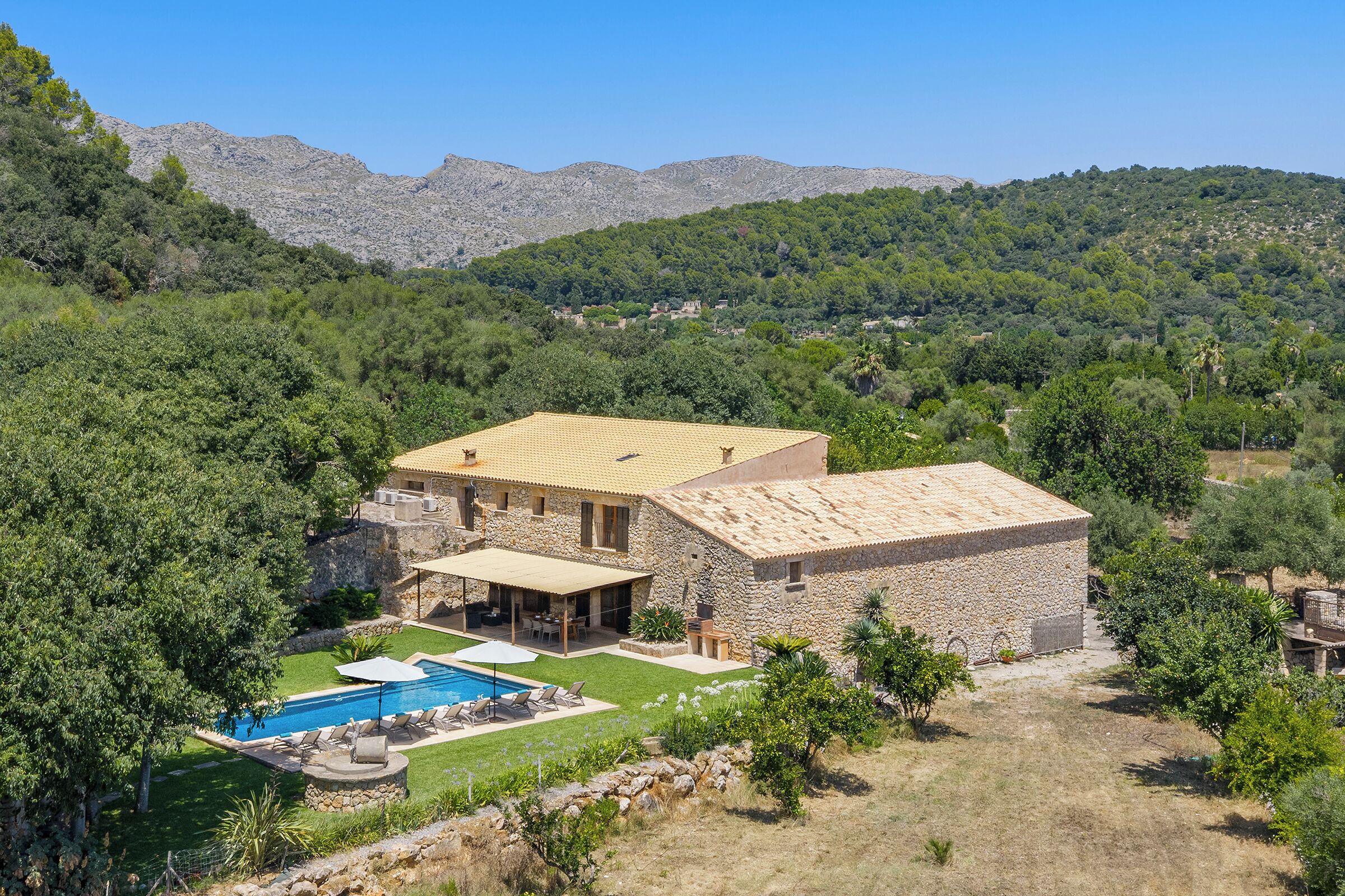 Une villa en pierre dotée d’une piscine, d’un espace extérieur aménagé et offrant une vue sur les collines environnantes.