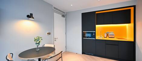Una cocina moderna con una decoración en tonos negro y amarillo, una mesa redonda con sillas y una pequeña planta en maceta sobre la mesa.