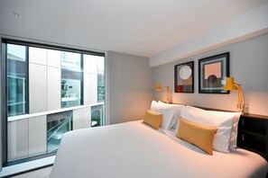 A modern hotel room with a large bed, two bedside lamps, and a view of the city through floor-to-ceiling windows. - Staycity Aparthotels, Dublin, Mark Street (Dublin)
